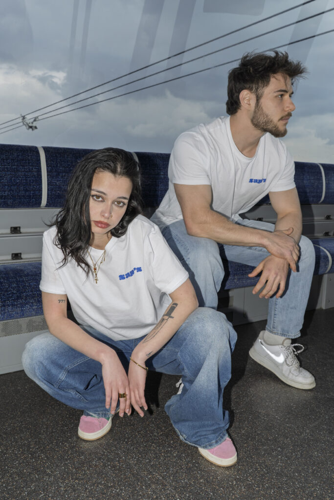 Photographie de mode urbaine à Toulouse : portrait assis de deux modèles portant les t-shirts d'une marque de vêtements locale.