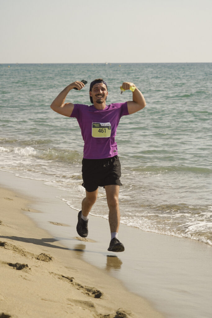 Coureur montrant ses muscles et célébrant son effort sur la plage du Biquet Trail.