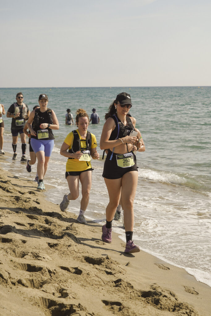 Groupe de coureurs de trail running en plein effort sur la plage pendant une compétition sportive.