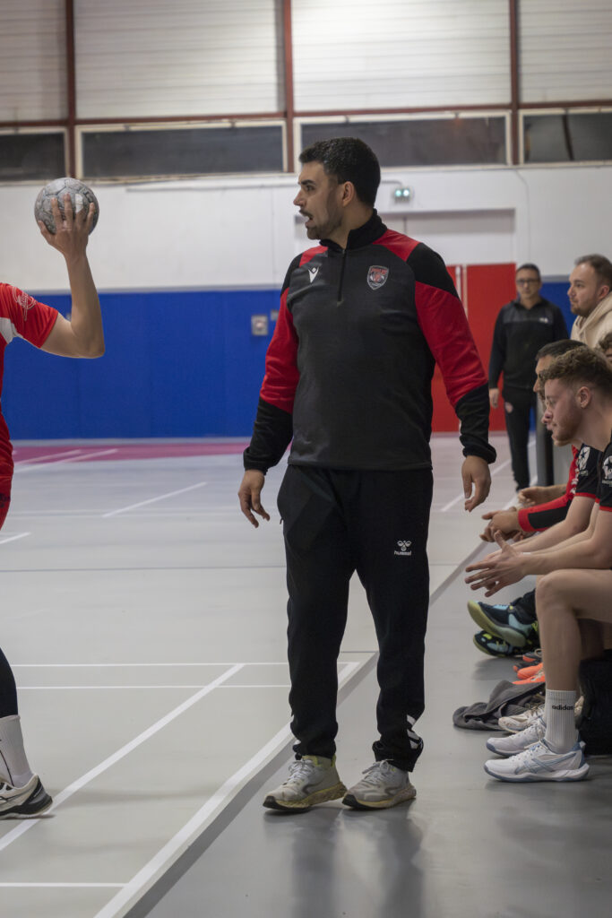 Banc de touche et entraîneur concentrés pendant un match de handball en Occitanie.