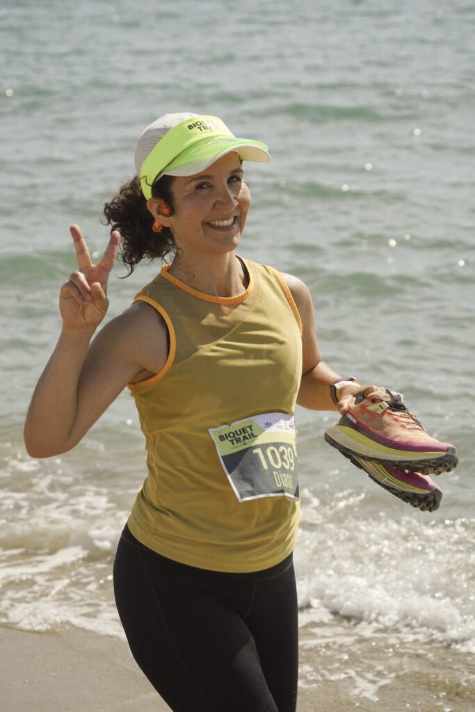 Reportage photo lors d'un événement sportif de trail running avec une coureuse tout sourire franchissant l'arrivée.